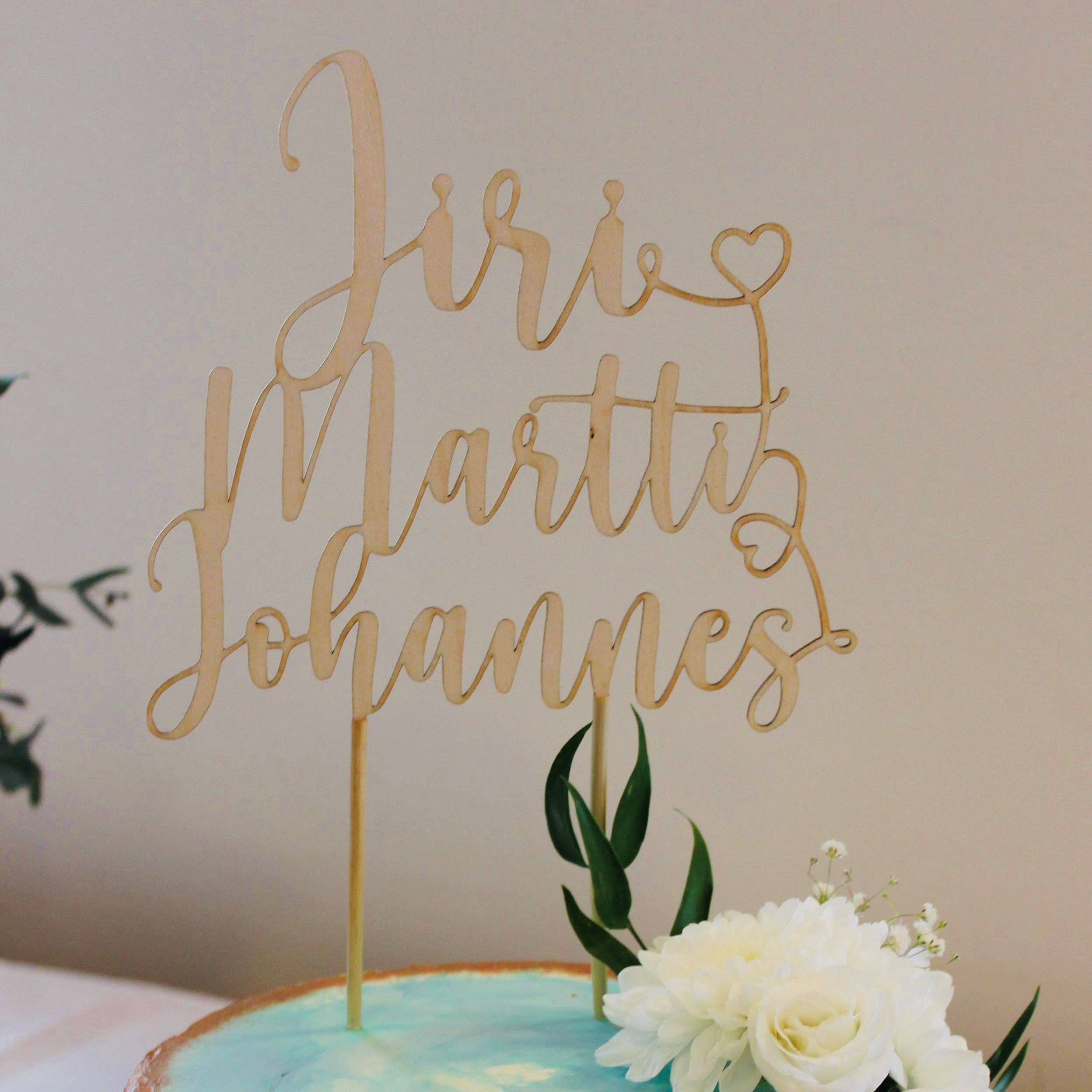 Koivuvanerista valmistettu nimikakkukoriste kolmella nimellä.