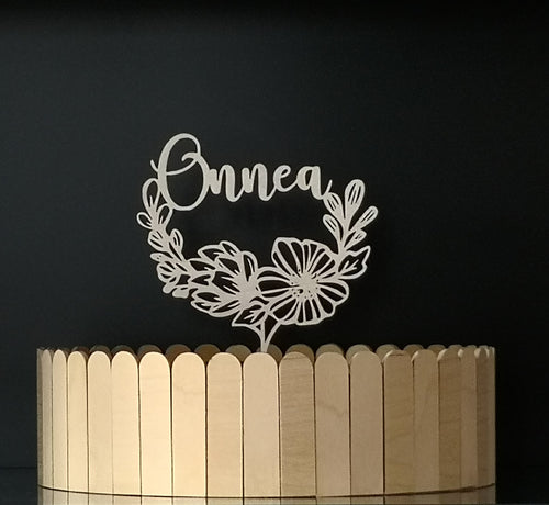 Kakkukoriste onnea -tekstillä ja kukkakoristeella