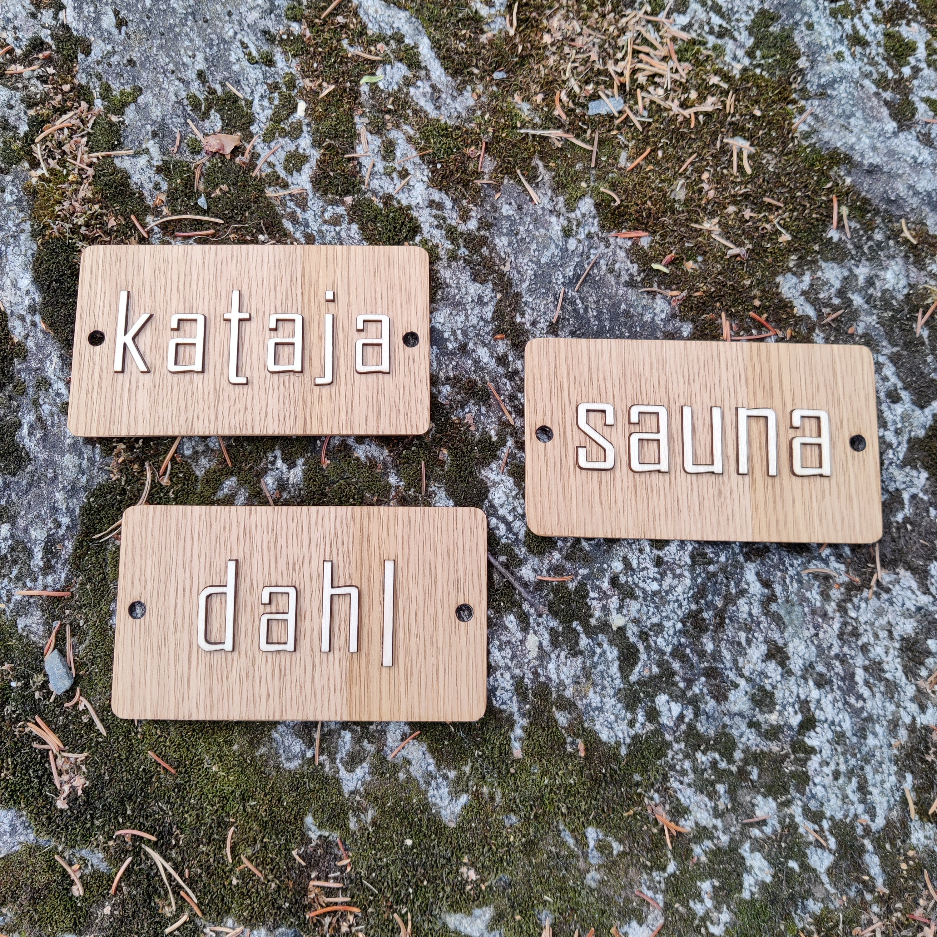 Tammikylttiin liimattu koivuvanerinen teksti asiakastyönä