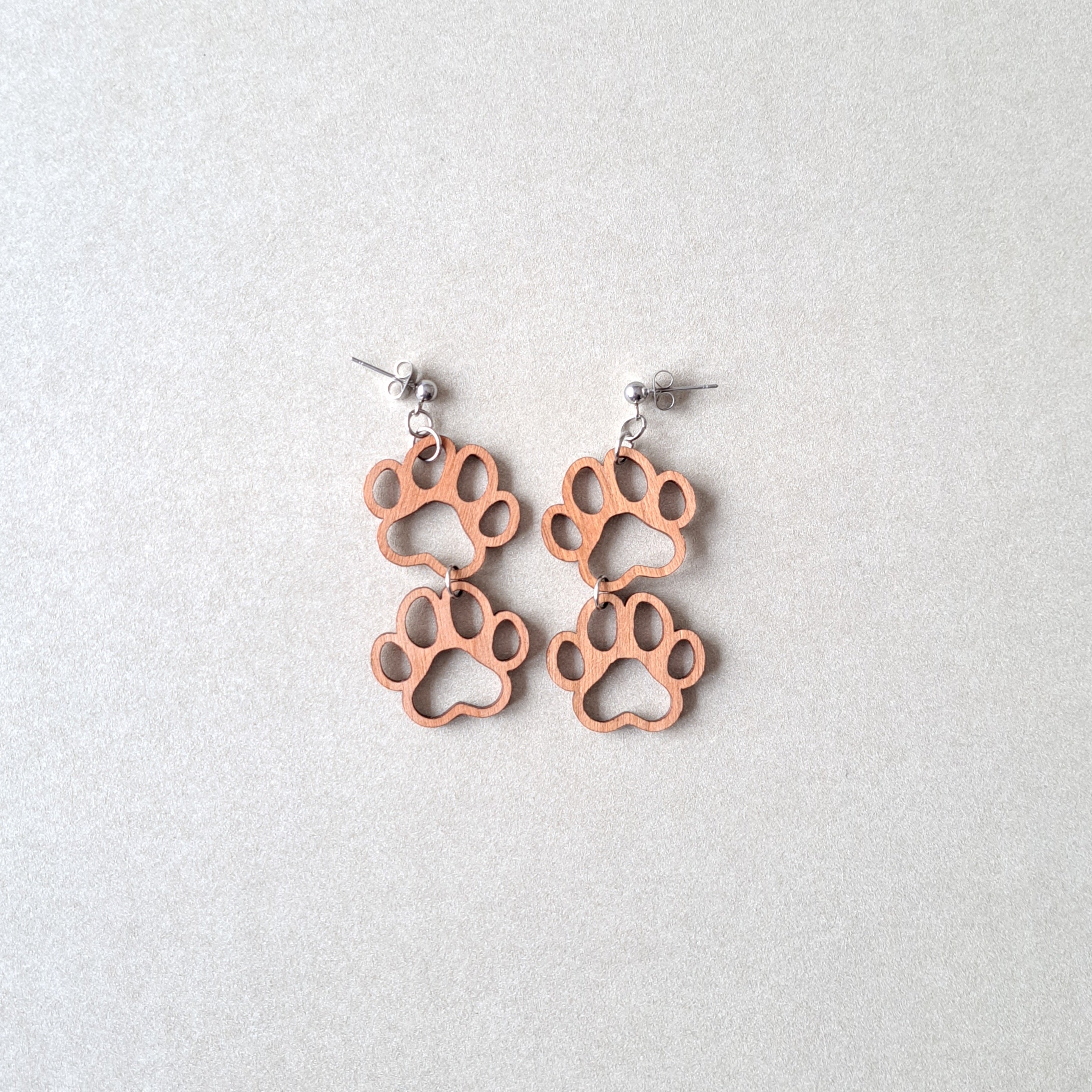 Kirsikkavanerista valmistetut tassu-korvakorut tapeilla.