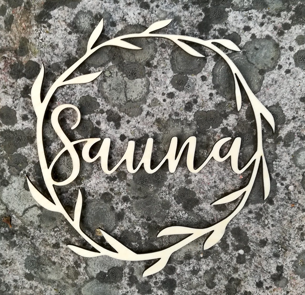 Koivuvanerista valmistettu köynnöskyltti sauna-tekstillä.