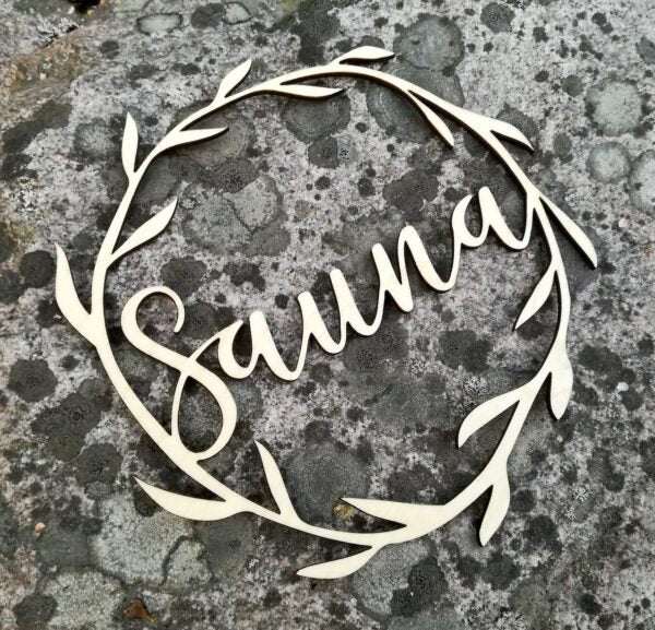 Koivuvanerista valmistettu köynnöskyltti sauna-tekstillä.